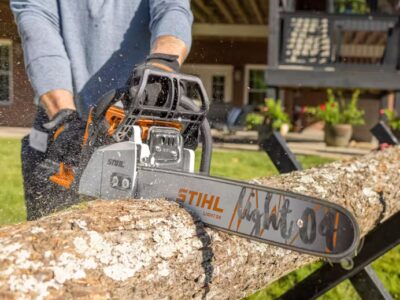 Man using a STIHL chainsaw to cut through a log outdoors, demonstrating professional power and reliability of STIHL equipment sold at RentX in Lindale, Texas