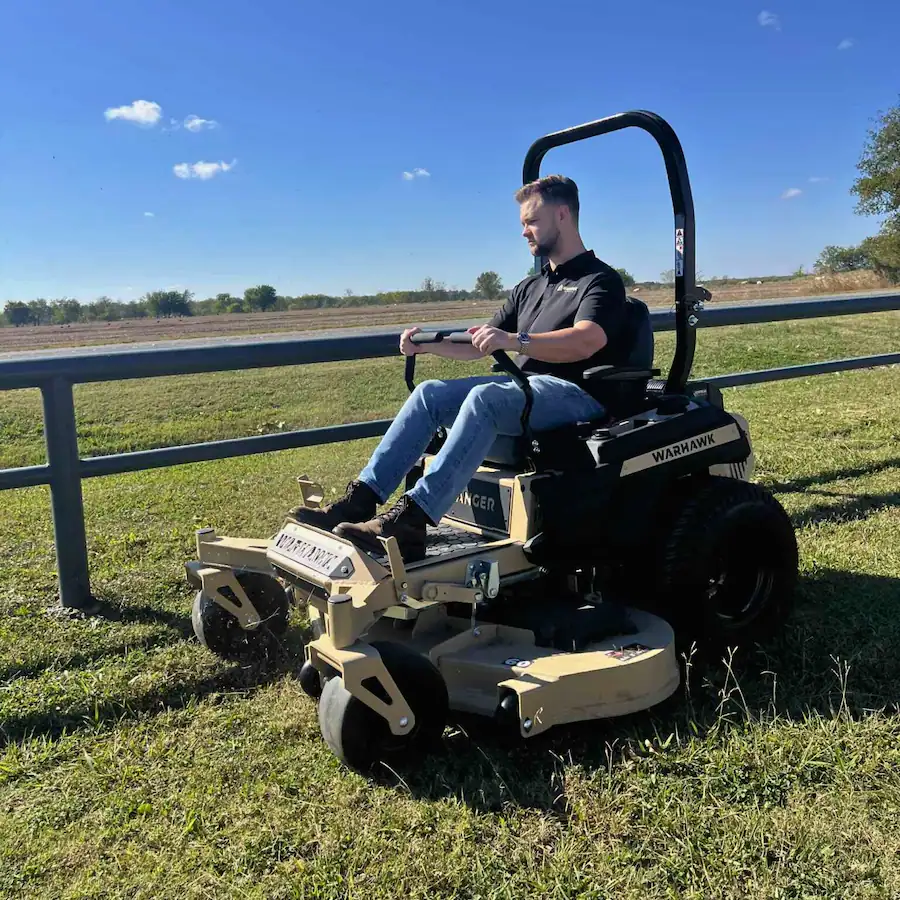 Warhawk zero turn mower cutting grass on open property, available at RentX in East Texas